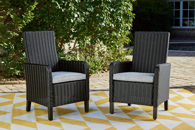 Set of two Ashley Furniture Beachcroft outdoor arm chairs with cushions, featuring woven design and comfortable seating for outdoor dining.
