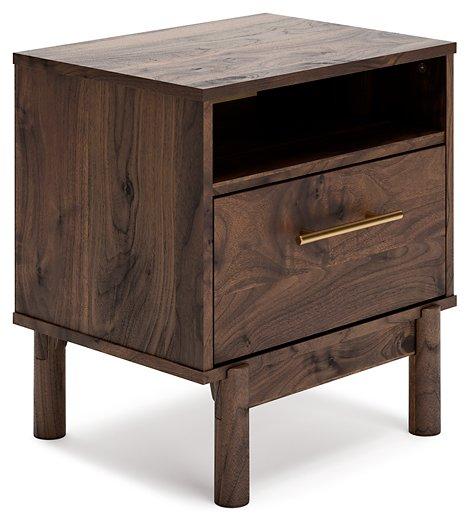 Ashley Furniture Calverson nightstand with two drawers, dark wood finish, and modern design, shown next to a bed.