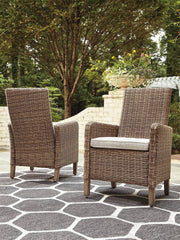 Set of two Ashley Furniture outdoor dining arm chairs with cushions, featuring woven design and sturdy metal frames for patio use.