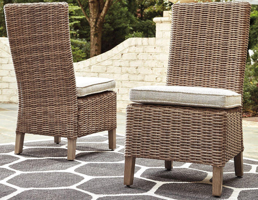 Set of two Ashley Furniture Beachcroft outdoor dining side chairs with cushions, featuring metal frames and woven seats.