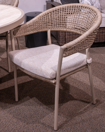 Set of four Ashley Furniture outdoor dining arm chairs with cushions, featuring woven rattan design and sturdy metal frames.