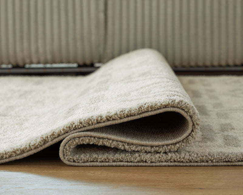 Large Maconville rug by Ashley Furniture, detailed view showing intricate pattern and plush texture on a neutral background.